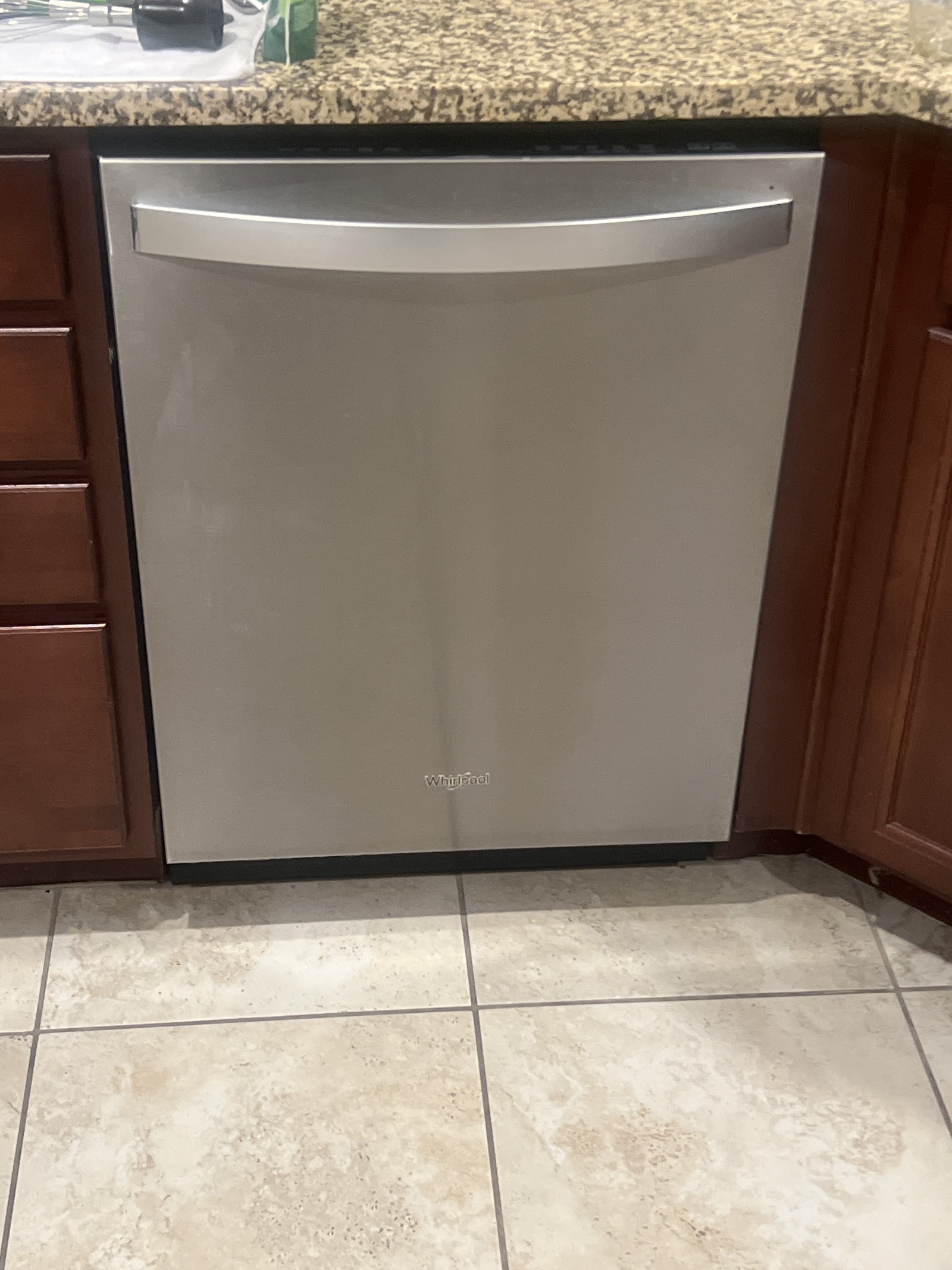 Stainless steel Whirlpool dishwasher installed under granite counter